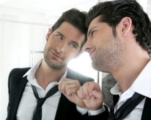 Handsome narcissistic suit proud young man looking himself in the mirror