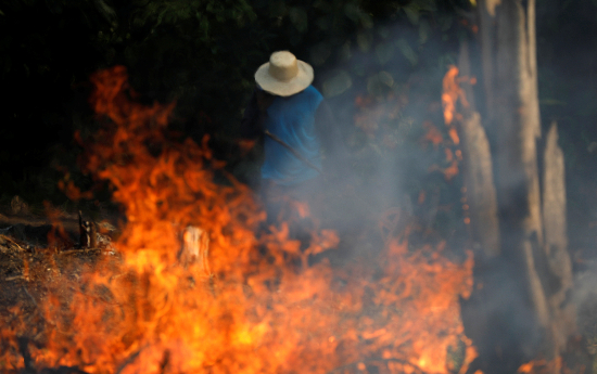 A man works in a burning tract of Amazon jungle as it is being cleared by loggers and farmers in Iranduba, Amazonas state, Brazil August 20, 2019. REUTERS/Bruno Kelly